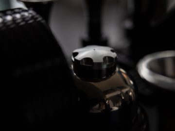 Close-up van Espresso Veloce RS Black Edition-machineonderdelen met een focus op de portafilterhandgreep.
