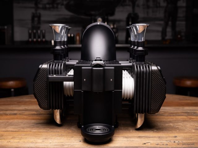High-end Espresso Veloce RS Black Edition machine op een houten aanrecht met een strak, modern design dat doet denken aan een motorfietsmotor.