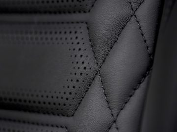 Close-up van de zwart lederen bekleding van de Ford Puma ST-Line Vignale met gedetailleerde stiksels en perforatiepatronen.