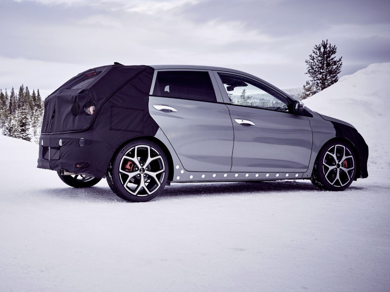 Een Hyundai i20 N met een beschermhoes op de achterste helft geparkeerd op besneeuwd terrein.