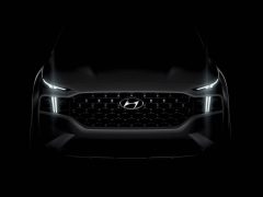Vooraanzicht van een zwarte Hyundai Santa Fe met verlichte koplampen en grille.