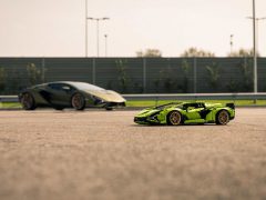 Twee Lamborghini-sportwagens op een open terrein, waarbij de dichtstbijzijnde aanzienlijk kleiner lijkt, wat erop wijst dat het een LEGO-schaalmodel of een perspectieftruc zou kunnen zijn.

