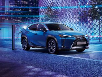 Een Lexus UX Electric opladen bij een station 's nachts in een stedelijke omgeving.