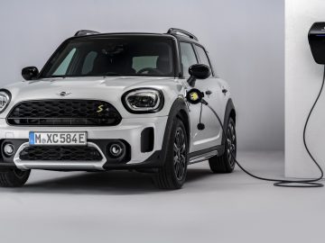 Een witte elektrische MINI Countryman SE laadt op bij een binnenlaadstation.