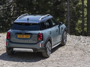 Een MINI Countryman geparkeerd op een onverharde weg in een bosrijke omgeving.