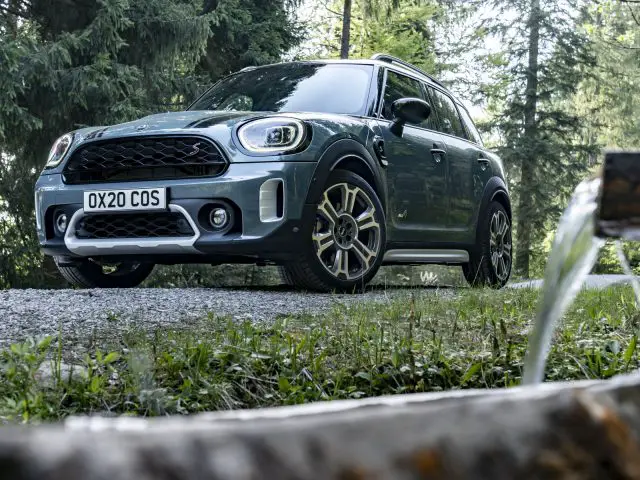 Een MINI Countryman geparkeerd op een onverharde weg in een bosrijke omgeving.