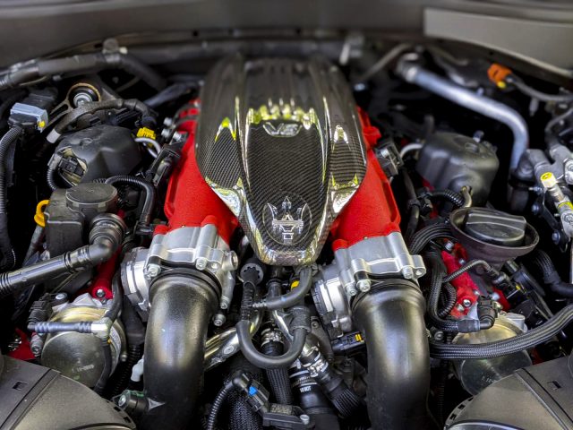 Close-up van de motorruimte van een Maserati Levante Trofeo met een V-vormige motor met koolstofvezelafdekkingen.