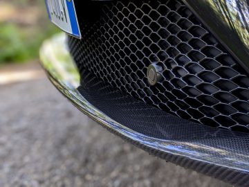 Close-up van de grille van een Maserati Levante Trofeo met een zeshoekig gaaspatroon en een parkeersensor.