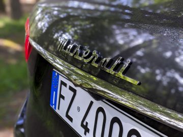 Close-up van een Maserati Levante Trofeo-embleem en een Europees kenteken op een auto.
