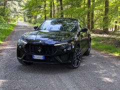 Een zwarte Maserati Levante Trofeo luxe SUV geparkeerd op een bosweg.