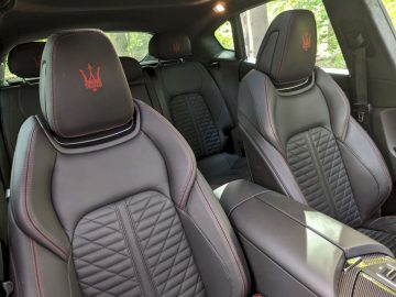 Zwart lederen auto-interieur met diamantgestikte stoelen en een geborduurd Maserati Levante Trofeo-logo op de hoofdsteunen.