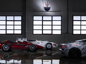 Drie Maserati-voertuigen in een showroom: een klassieke rode raceauto, een witte vintage raceauto met nummer 10 en een moderne Maserati MC20 in een zwart-witte camouflageverpakking
