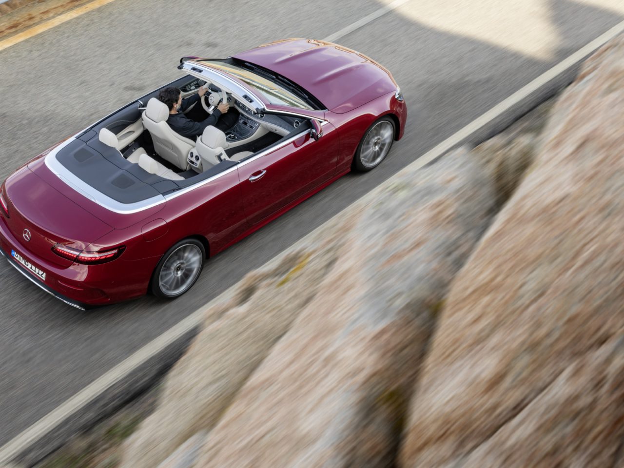 Rode Mercedes-Benz E-Klasse cabriolet rijdend op de kustweg.