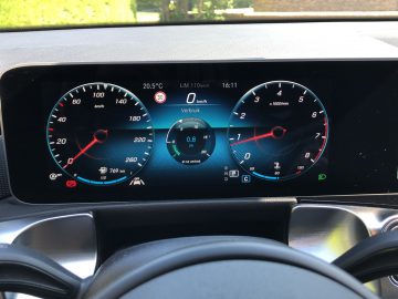 Digitaal autodashboard in een Mercedes-Benz GLB met snelheidsmeter, toerenteller, brandstofmeter en infotainmentsysteem met stilstaande navigatie.