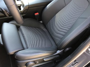 Close-up van de voorstoelen van een Mercedes-Benz GLB met de nadruk op de bedieningselementen voor de bekleding en de stoelverstelling.