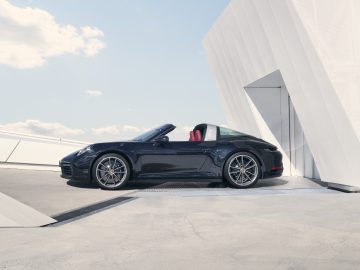 Zwarte Porsche 911 Targa sportwagen geparkeerd op een moderne structuur onder een heldere hemel.