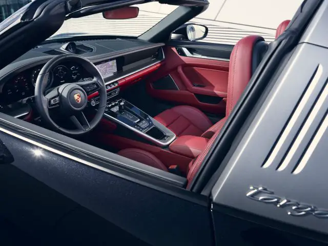 Luxe rood en zwart interieur van een Porsche 911 Targa met de deur open, met het dashboard, het stuur en de middenconsole.