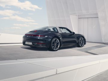 Een zwarte Porsche 911 Targa converteerbare sportwagen geparkeerd op een modern, minimalistisch dak.