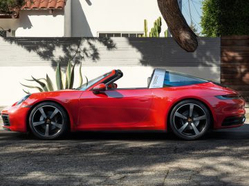 Rode Porsche 911 Targa geparkeerd aan de stoeprand in een zonnige woonstraat.