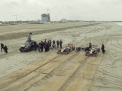 Een filmploeg en cast verzamelden zich op een strand met apparatuur voor een 
