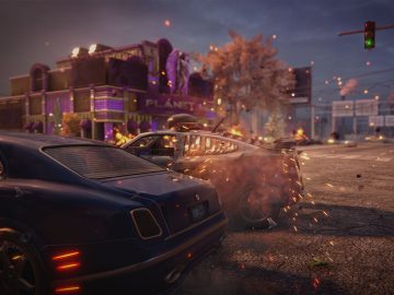 Een still uit Saints Row The Third Remastered met een auto-achtervolgingsscène met een exploderend voertuig nabij een gebouw met het opschrift "planet".