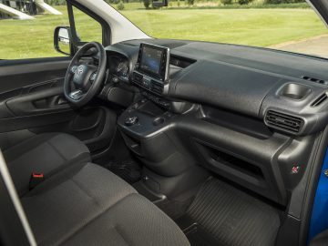 Binnenaanzicht van een Toyota ProAce City met het dashboard, het stuur, het infotainmentsysteem en de voorstoelen.