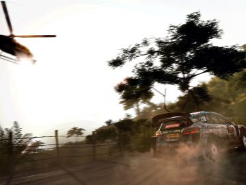 WRC 9-gameplay bestaat uit rallyautoraces op een stoffige baan terwijl bij zonsondergang een helikopter overvliegt.