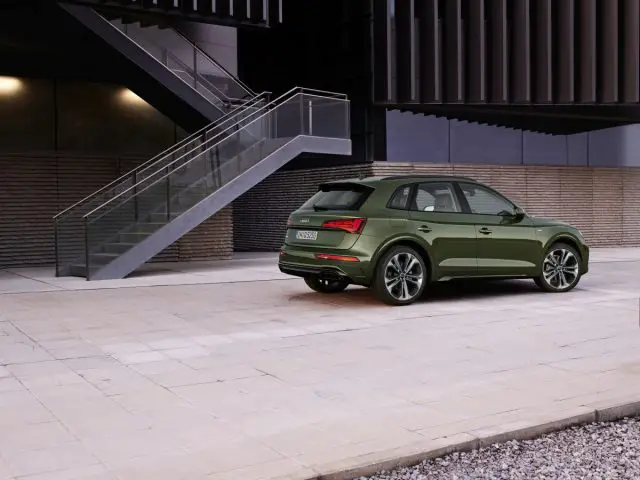 Een groene Audi Q5 SUV geparkeerd naast een trap in een stedelijke omgeving.