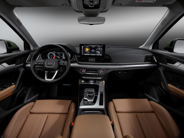 Binnenaanzicht van de Audi Q5 met het dashboard, het infotainmentsysteem en de lederen stoelen.
