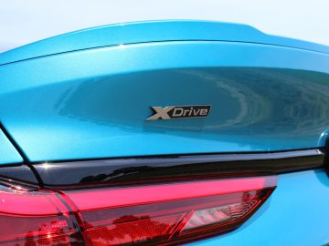 Achteraanzicht van een BMW 2 Serie Gran Coupé, met de nadruk op het "xdrive"-embleem op het kofferdeksel.