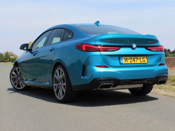 Blauwe BMW 2 Serie Gran Coupé geparkeerd langs de weg op een zonnige dag.