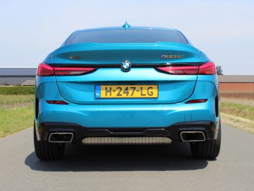 Achteraanzicht van een blauwe BMW 2 Serie Gran Coupé op een weg.