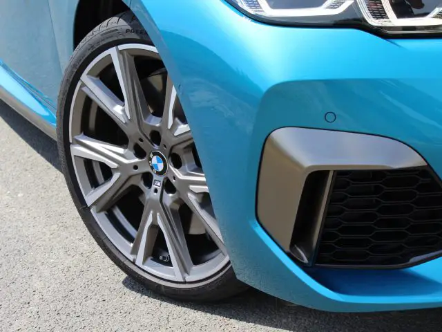 Close-up van het voorwiel van een blauwe BMW 2 Serie Gran Coupé en een deel van de grille.