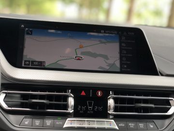 Autodashboard in de BMW 2 Serie Gran Coupé met een navigatiesysteemdisplay en klimaatregeling.