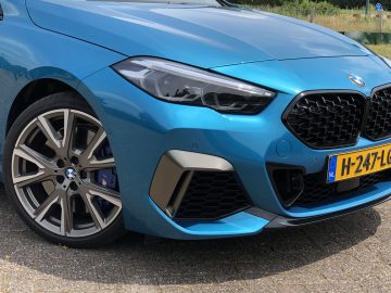 Close-up van de voorkant van een blauwe BMW 2 Serie Gran Coupé, met de grille, de koplamp en het stuur.