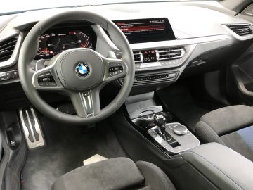 Binnenaanzicht van een modern BMW 2 Serie Gran Coupé-voertuig met het stuur, het dashboard, de middenconsole en de versnellingspook.