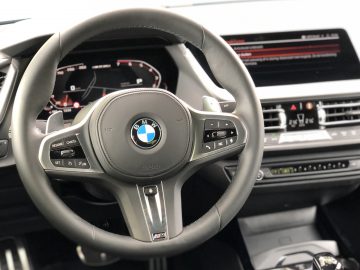 Binnenaanzicht van een BMW 2 Serie Gran Coupé-voertuig, gericht op het stuur met digitaal dashboard op de achtergrond.