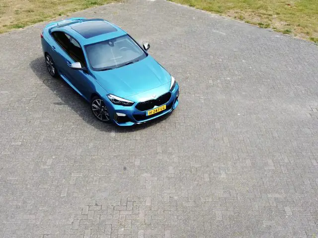 Een blauwe BMW 2 Serie Gran Coupé geparkeerd op een verhard terrein, van bovenaf gezien.