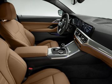 Modern BMW 4 Serie Coupé-interieur met lederen stoelen en touchscreen dashboardbediening.