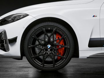 Close-up van het voorwiel van een BMW 4 Serie Coupé, met de lichtmetalen velg, de performance-remklauw en het M Performance-embleem.