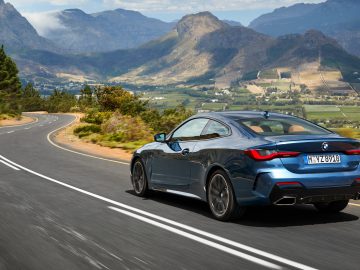 Een BMW 4 Serie Coupé die over een bergweg rijdt met mooie uitzichten.
