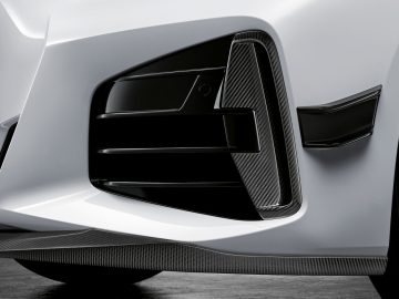 Close-up van de voorbumper en het luchtinlaatrooster van een BMW 4 Serie Coupé met koolstofvezelaccenten.