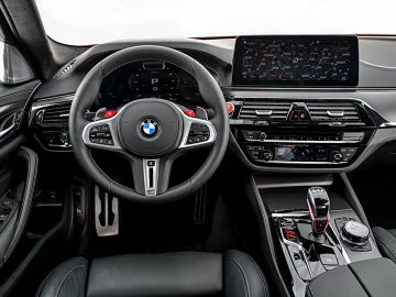 Binnenaanzicht van een BMW M5-voertuig met het stuur, het digitale dashboard en de middenconsole.