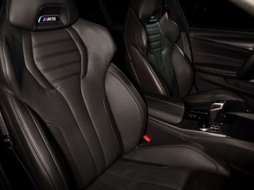 Binnenaanzicht van een BMW M5 met zwart lederen sportstoelen en middenconsole.
