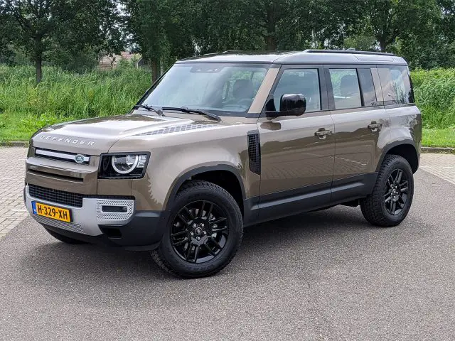 Een modern Land Rover Defender-voertuig staat geparkeerd aan de kant van een weg.