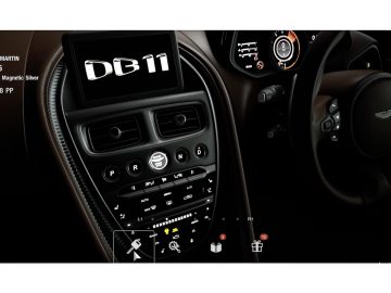 Binnenaanzicht van een Aston Martin DB11 met de nadruk op de middenconsole en het dashboard, met prominent een PlayStation 5 met Gran Turismo 7.