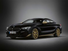 Zwarte BMW 8 Serie sportcoupé met goudkleurige wielen op een grijze achtergrond.