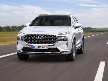 Een witte Hyundai Santa Fe SUV die overdag op een asfaltweg rijdt.