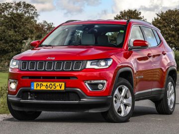 Rode Jeep Compass geparkeerd op een landweg.