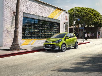 Kia Picanto elektrische auto geparkeerd in een stedelijke straat vlakbij een gebouw met grote ramen.